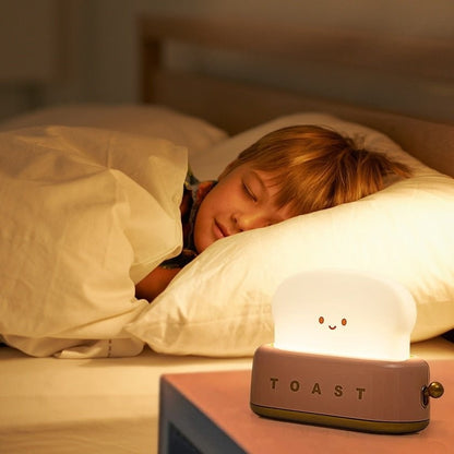 Pink toast night light on a bedside table beside a sleeping child