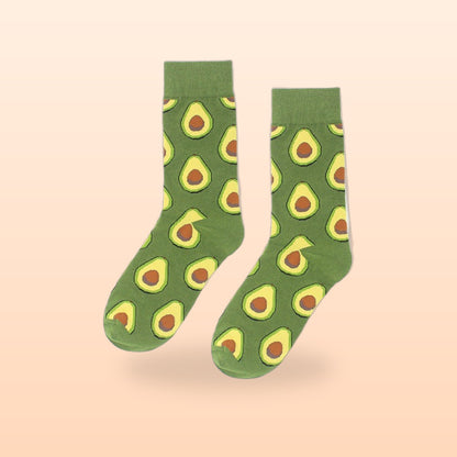 Pair of green crew socks with a repeating halved avocado pattern, on a peach background