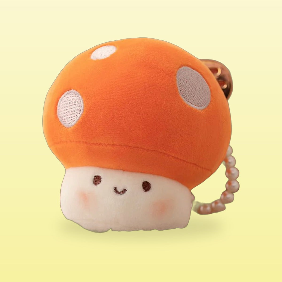 Orange mushroom plush keychain with white spots and a smiling face