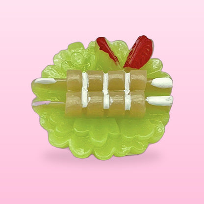 Skewer plate miniature food fridge magnet on a green scalloped dish, on a pink background