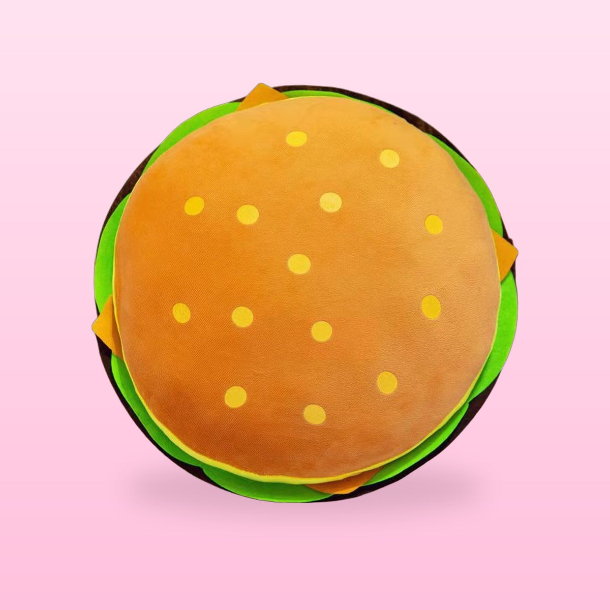 Hamburger plush pillow with an orange bun and green lettuce, top view on a pink background