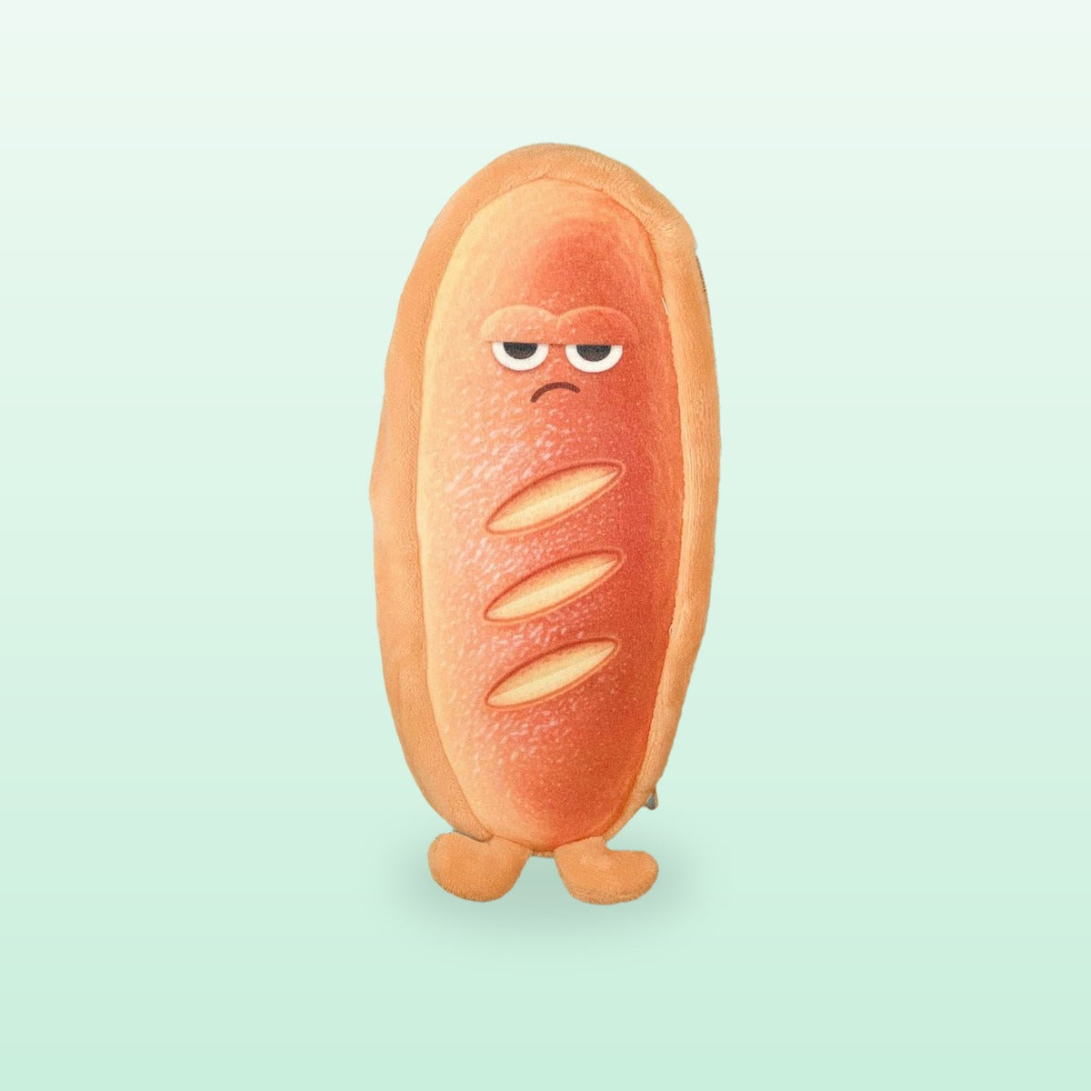 Grumpy baguette plush pencil case with a long scored crust, on a mint background