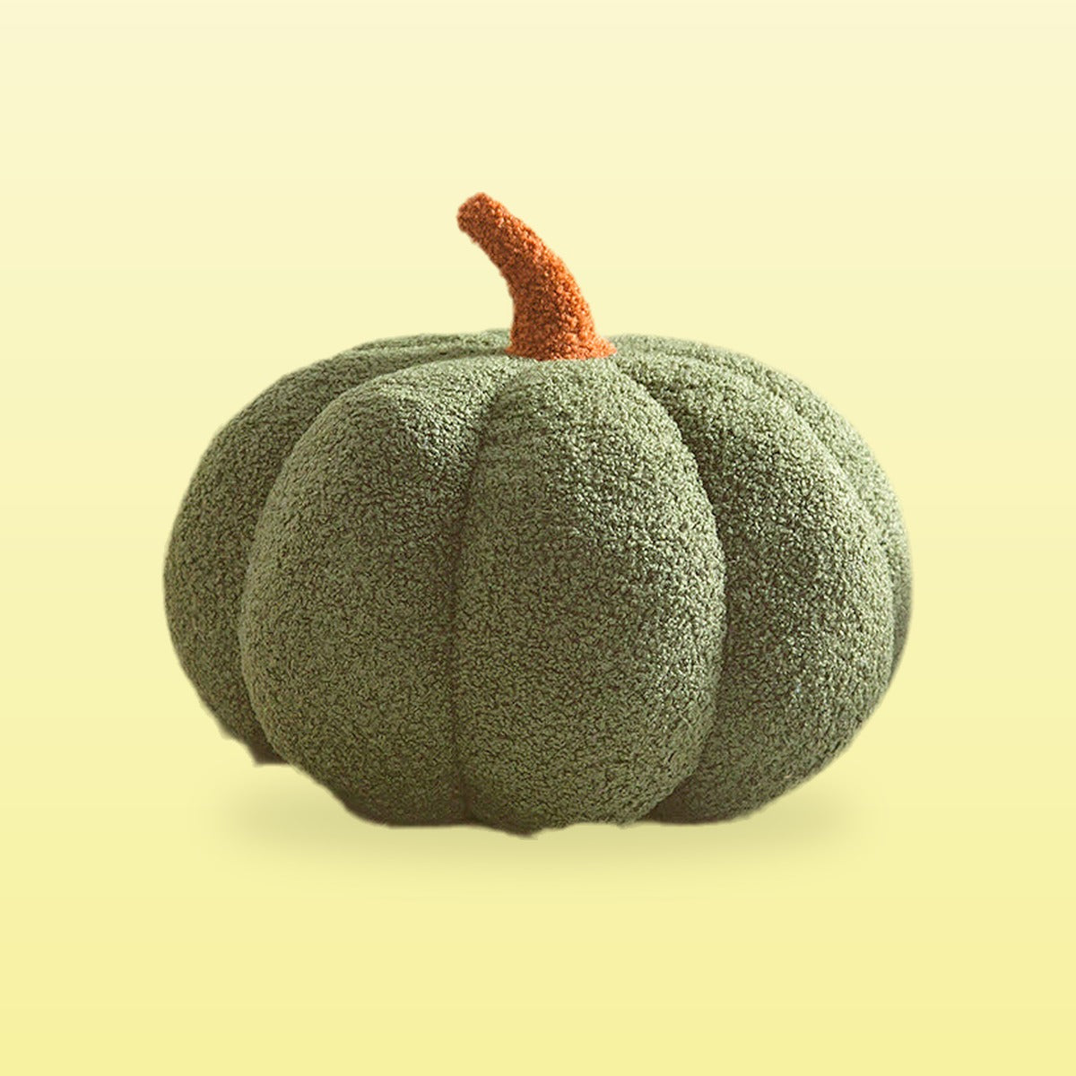 Teddy pumpkin plush cushion, forest green with a brown stem, on a butter yellow background