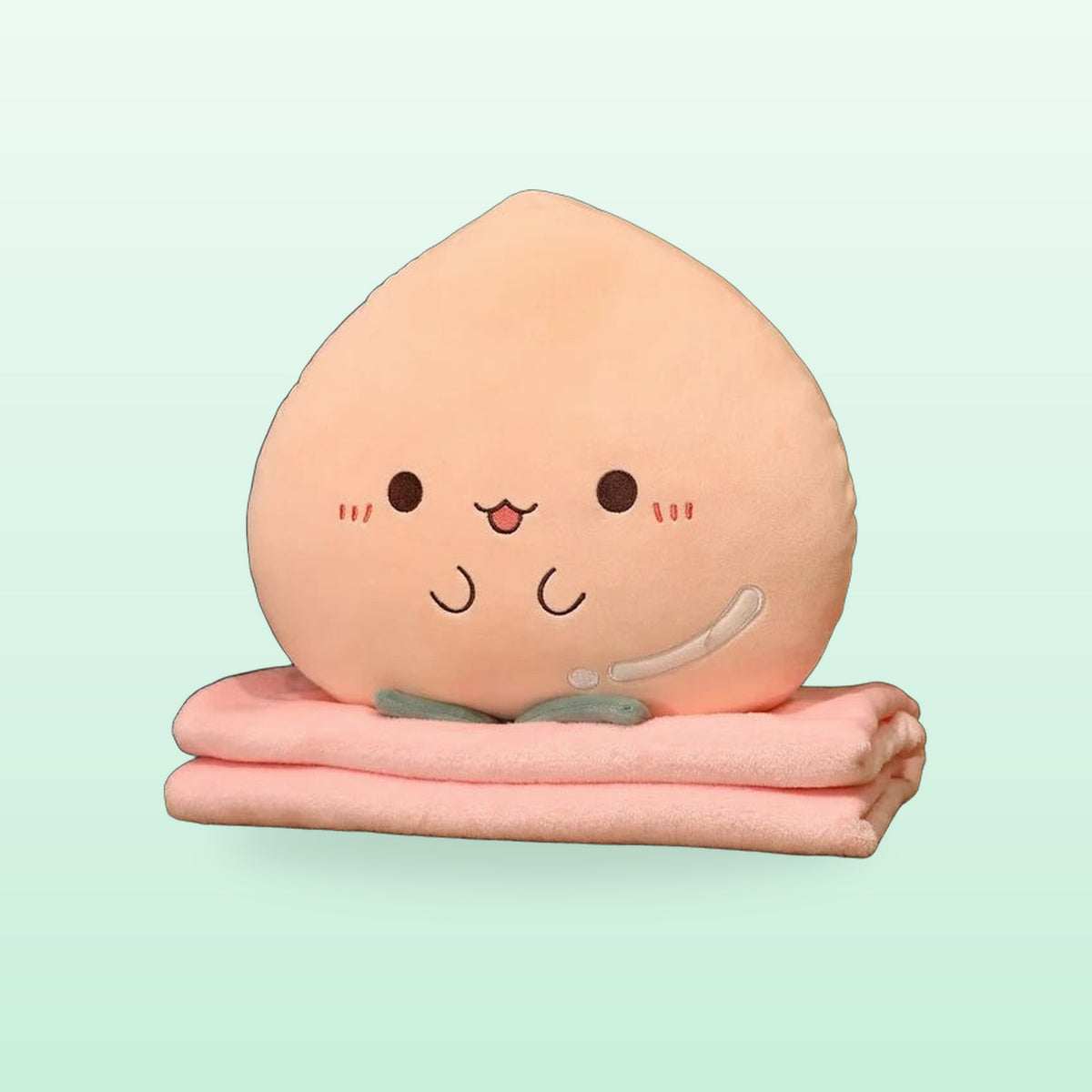 Peach plush pillow with a smiling face on its folded pink blanket, on a mint green background
