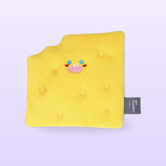 Yellow cheese slice crinkle dog toy with an embroidered face and bite mark, on a lilac background