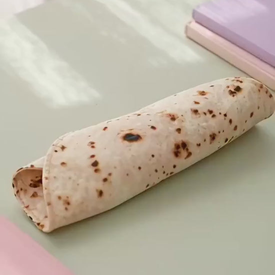 Burrito pencil case unrolling on a desk to show the tortilla print and pen strap