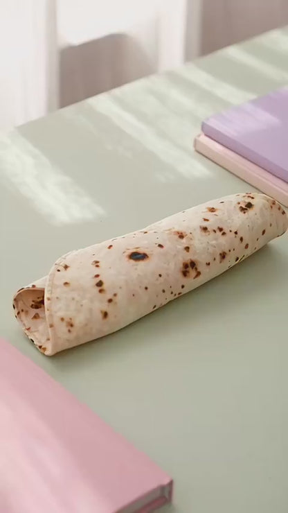 Burrito pencil case unrolling on a desk to show the tortilla print and pen strap