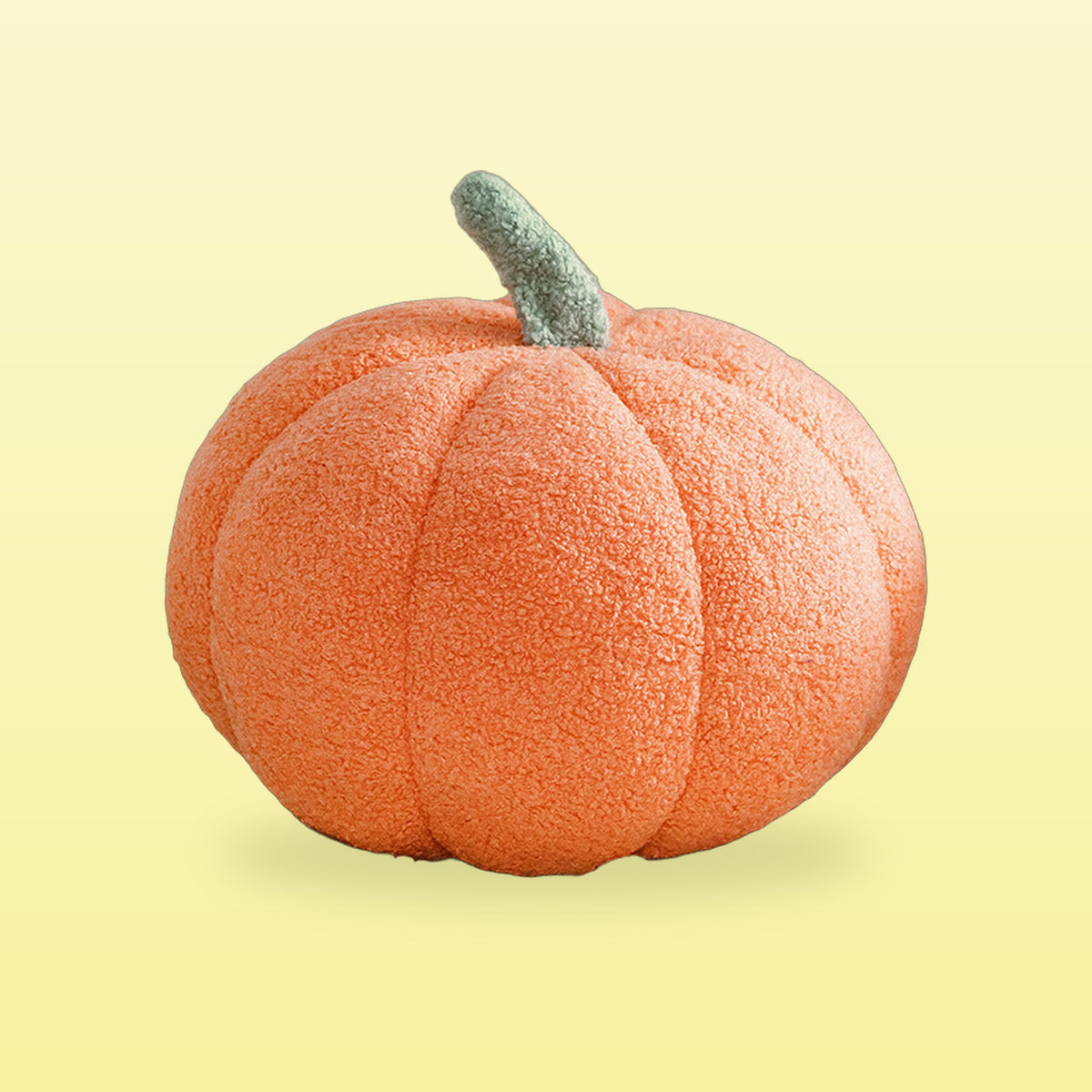 Peach orange teddy pumpkin plush cushion with a sage stem, on a butter yellow background