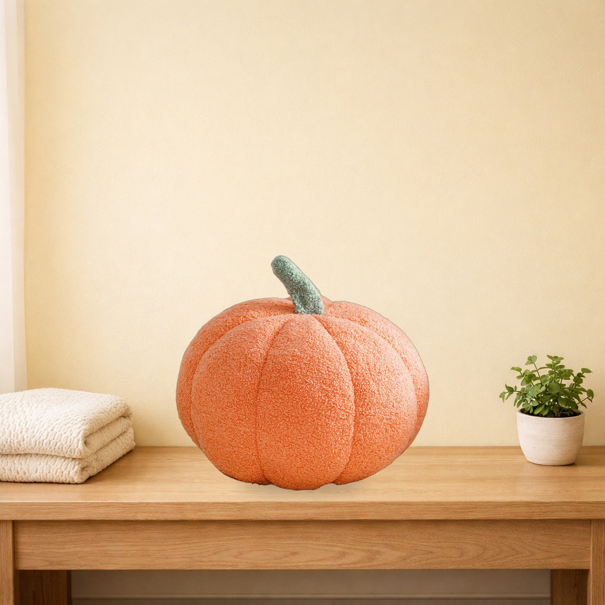 Peach orange teddy pumpkin plush cushion on a light oak console table