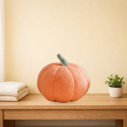 Peach orange teddy pumpkin plush cushion on a light oak console table