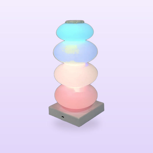 Candy skewer lamp with four glowing pastel candy shapes on a white base, on a lilac background