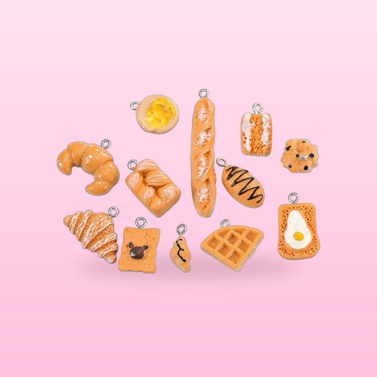 Resin bakery charms with silver loops, croissants, baguette, egg toast and waffle, on a pink background