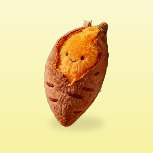 Roasted sweet potato plush charm with a smiling orange filling, on a butter yellow background