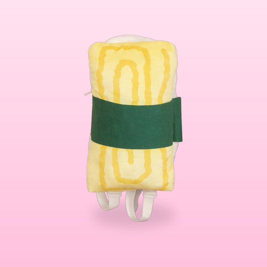 Omelette sushi plush backpack with a green seaweed band and white straps, on a pastel pink background