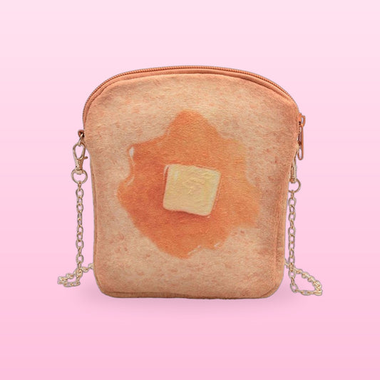 Butter toast crossbody bag with a gold chain strap on a pink background