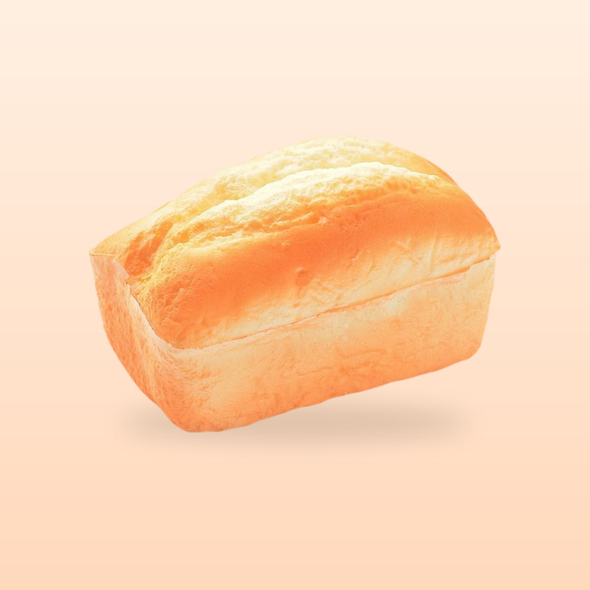 Split top loaf slow rise bread squishy, on a soft peach background