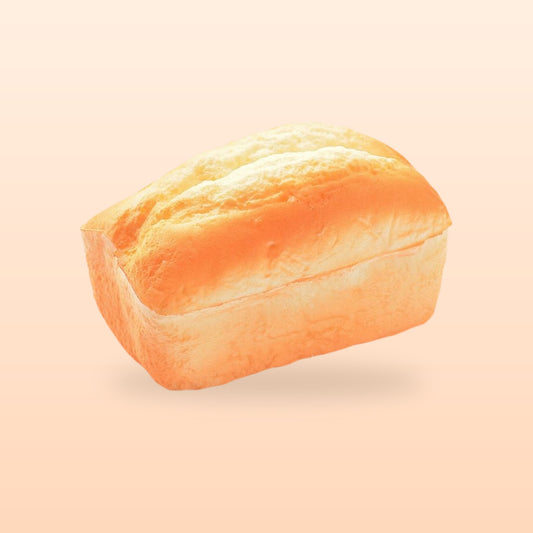 Split top loaf slow rise bread squishy, on a soft peach background