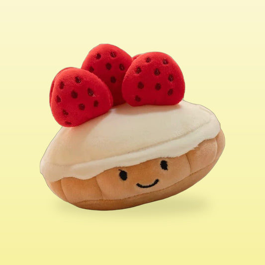 Strawberry muffin plush with three red strawberries, cream icing and a smiling face on a butter yellow background