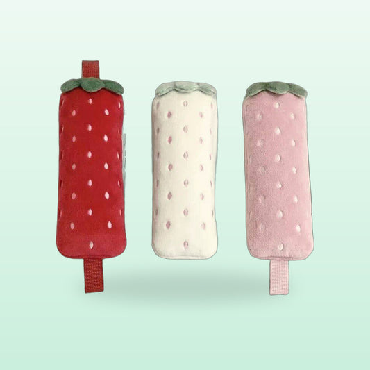 Red, white and pink strawberry plush pencil cases side by side, on a mint background