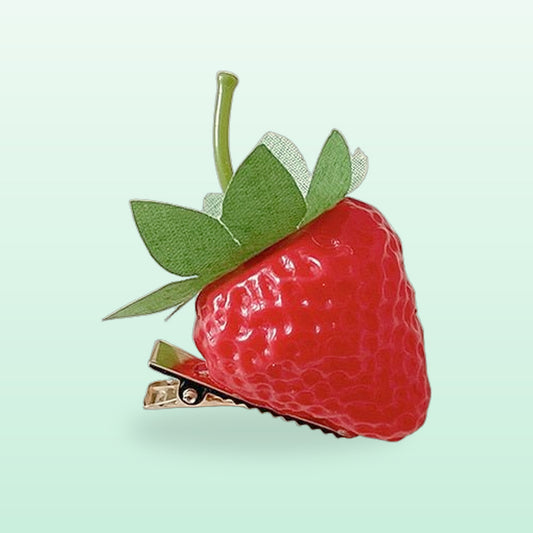 Strawberry resin hair clip with green leaves and a gold clip, on a mint background