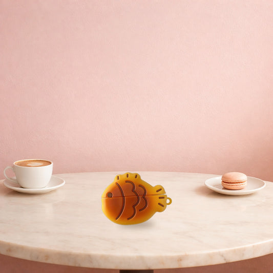 Taiyaki fish AirPods case on a marble café table