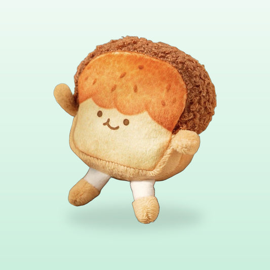 Golden toast plush keychain with a smiling face and fluffy crust, on a mint green background