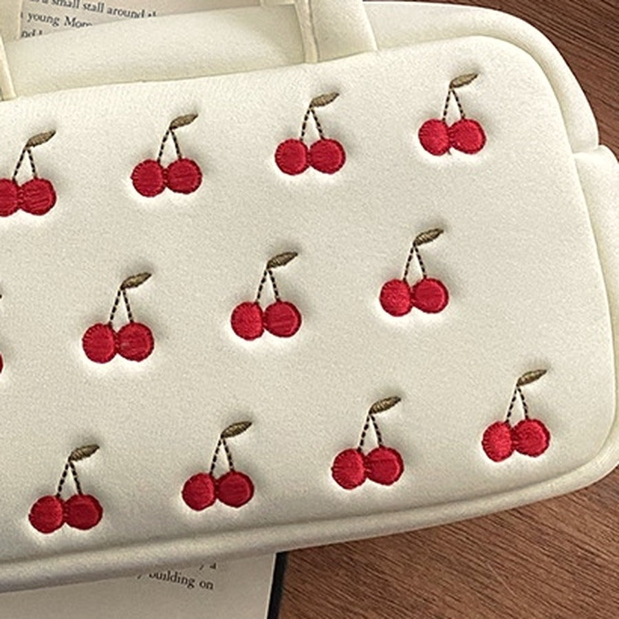 Close up of the red embroidered cherry pairs on the cream vanity bag