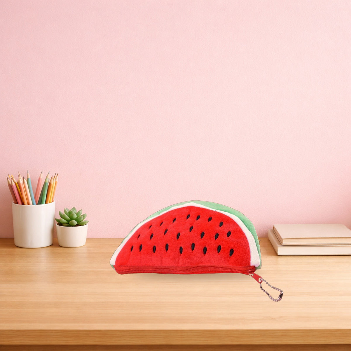 Red watermelon plush pencil case on a light oak study desk